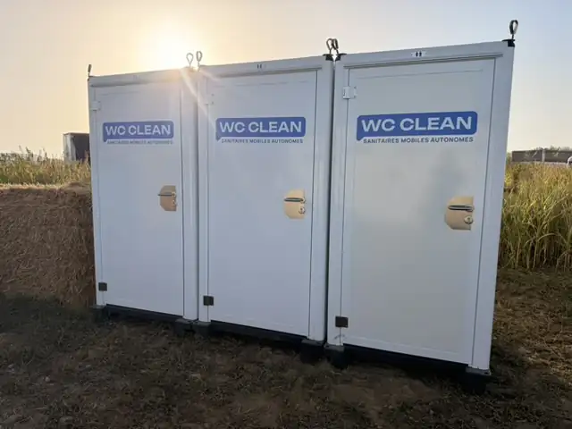 Toilettes mobiles Premium : trois cabines WC Clean alignées au coucher du soleil