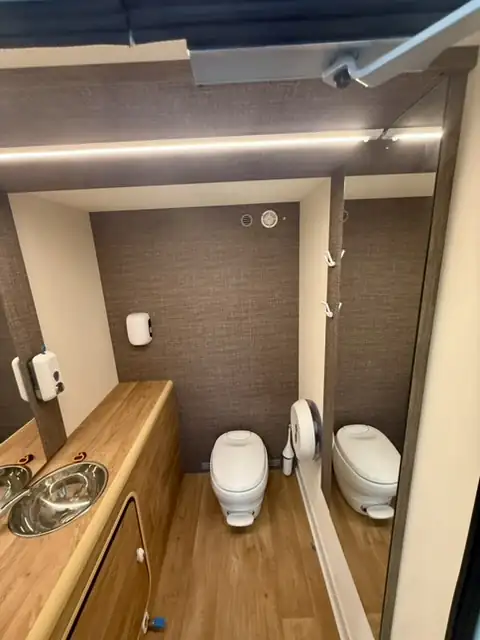 Sanitaires autonomes Prestige, intérieur : plan vasque en bois, WC et éclairage soigné